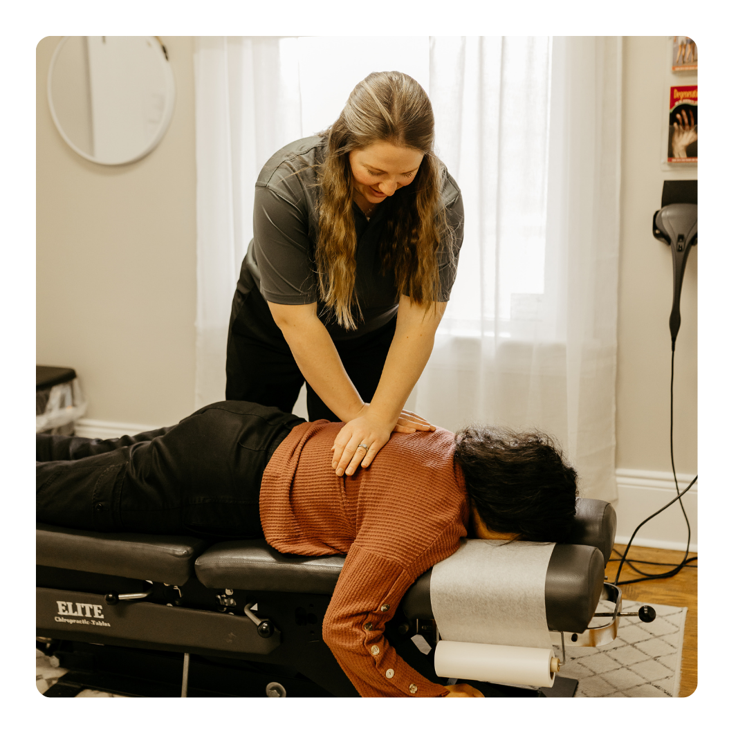 A therapist massages the back of a patient lying on a table.